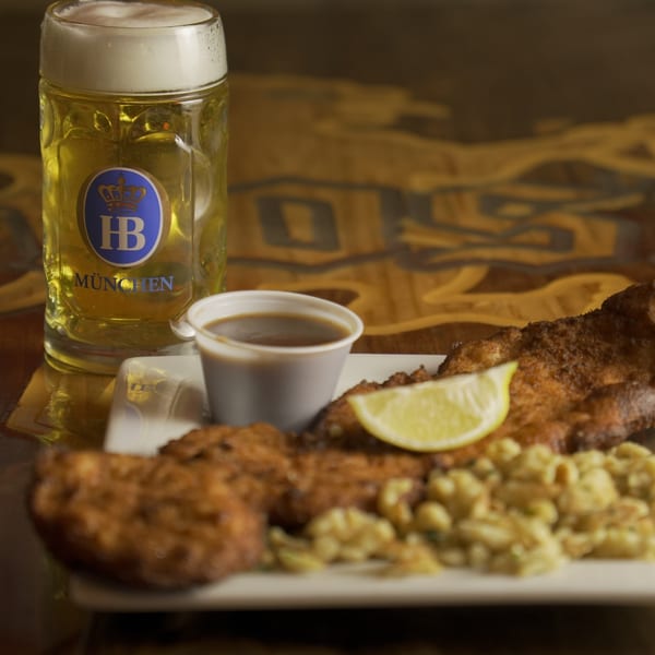 Crispy fried fish with spaetzle, a lemon wedge, and a mug of Hofbräu München beer.